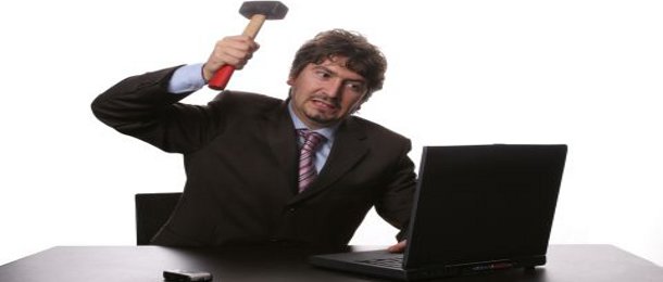 Fustrated businessman in his office threatening to destroy his PC with a hammer out of sheer frustration